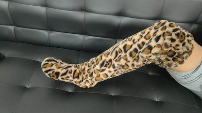 Leopard print leg warmers worn by a person on a black leather couch.